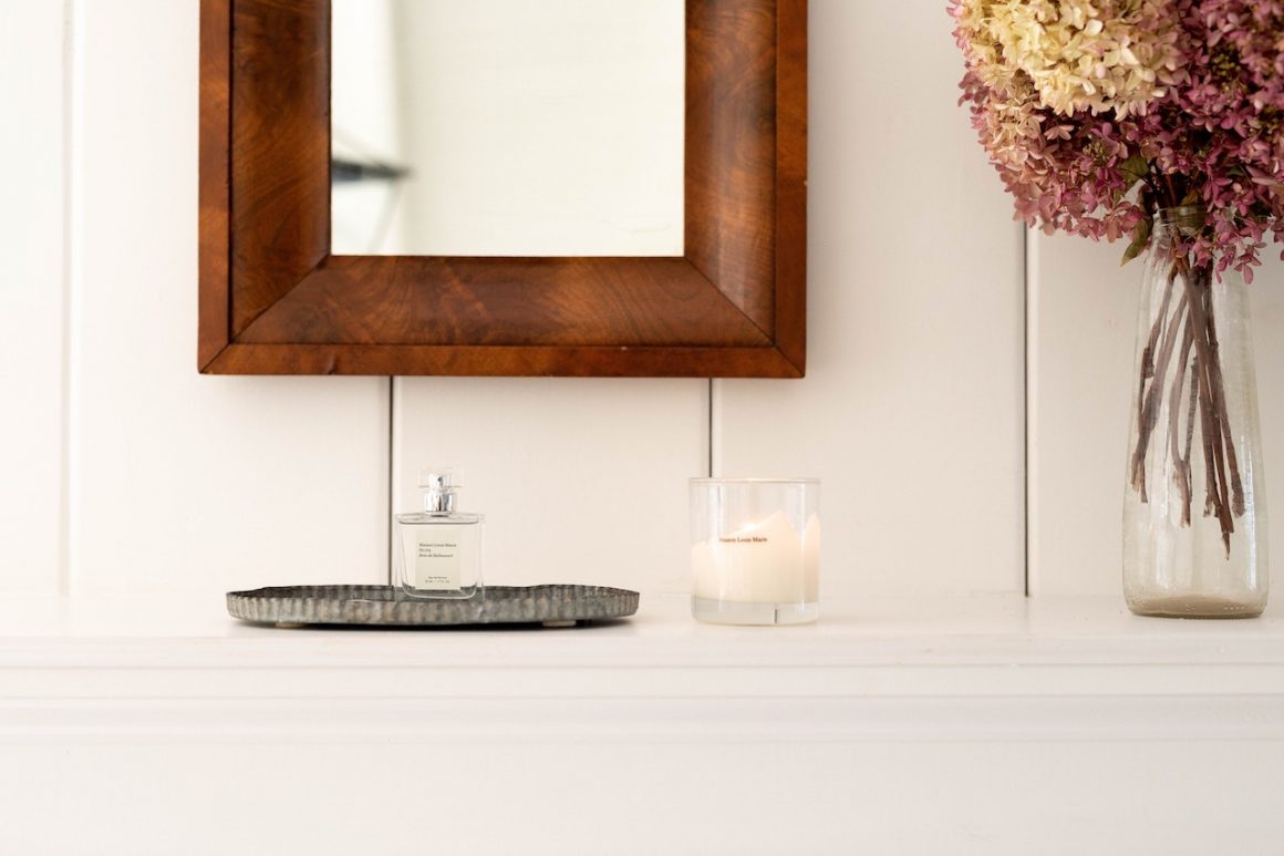 flowers, perfume and a lighted candle on a mantlepiece