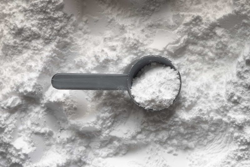 A scoop of creatine powder sitting on top of more creatine powder